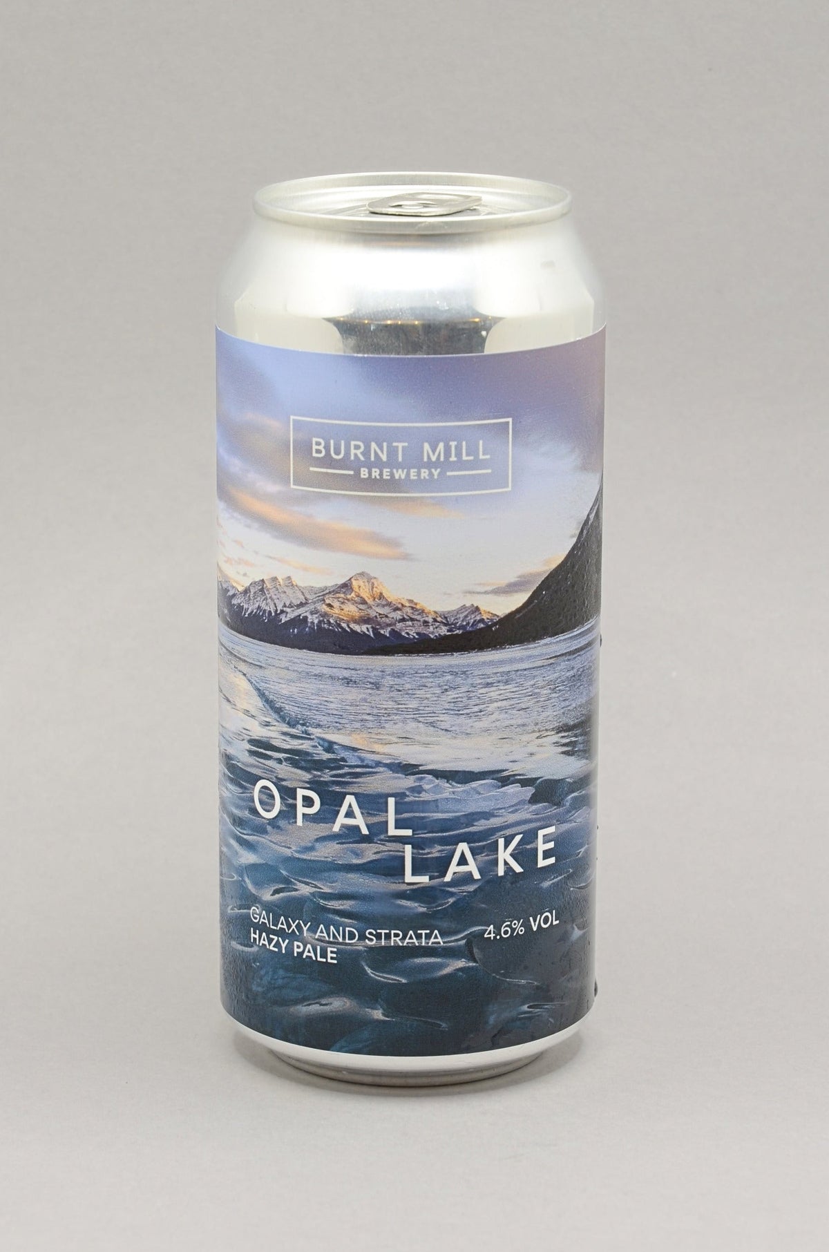 A 440ml aluminium can of Burnt Mill Brewery Opal Lake IPA, featuring a scenic label of a mountain lake under a blue and purple sky, set against a neutral gray background.