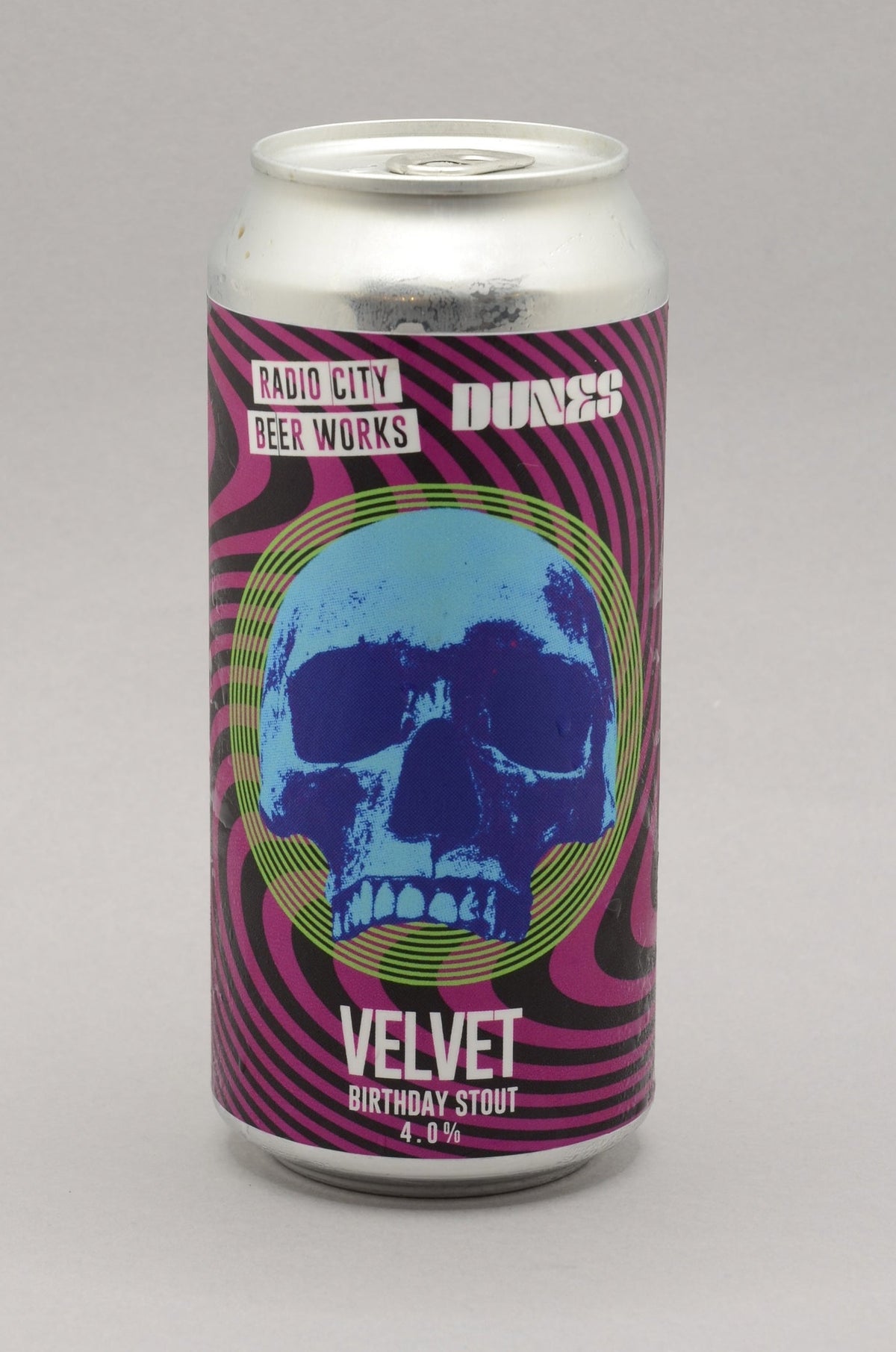 A 12 fl oz aluminum can of Velvet Birthday Stout by Local City Beer Works, featuring a purple and pink psychedelic swirl pattern with a blue skull graphic in the center, set against a neutral gray background.
